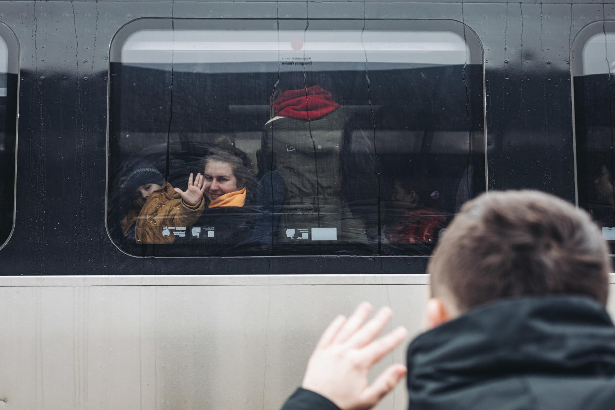 A man waves to his wife and son at a train station in Kyiv on Tuesday.