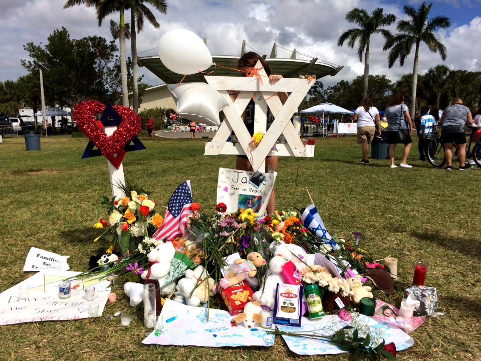 <p>A girl writes a note at a makeshift memorial for Marjory Stoneman Douglas High School shooting victim, Jaime Guttenberg, at Pine Trail Park, Parkland, Fla., Feb. 19, 2018. (Photo: Mindy Katzman/Yahoo News) </p>