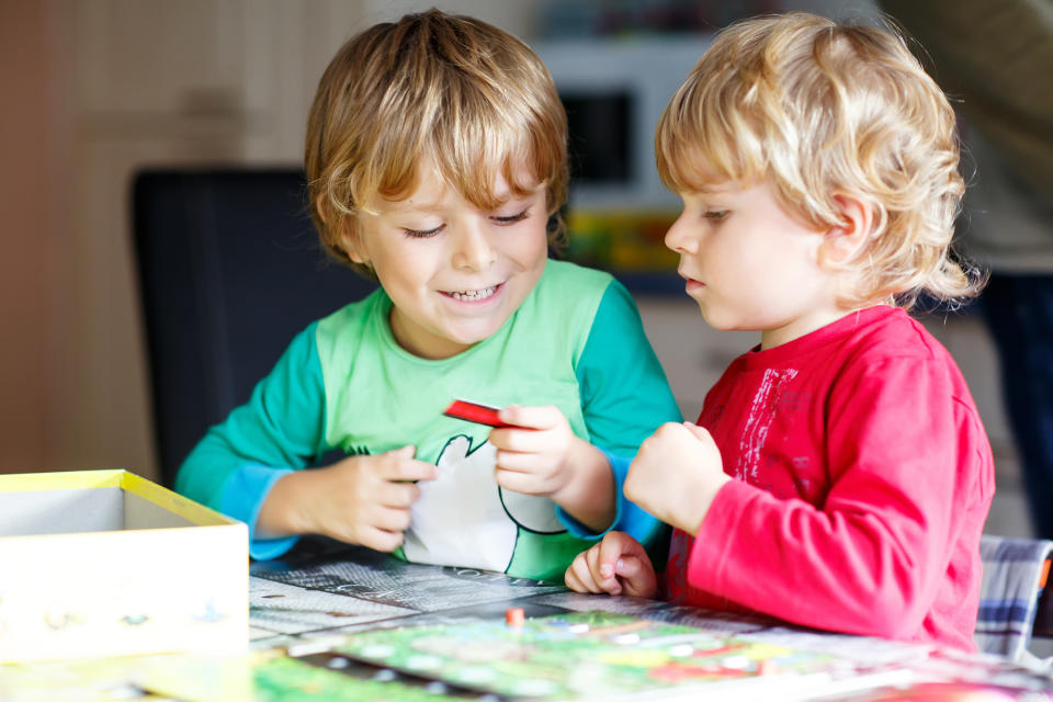 Two children sitting at a table playing a board game.