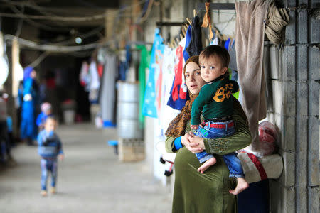 A pregnant Syrian woman carries her child at a compound housing Syrian refugees in Sidon, southern Lebanon January 25, 2017. REUTERS/Ali Hashisho