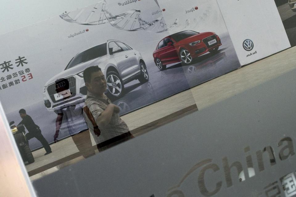 Reflected in a glass door, visitors walk past Audi's car advertisement at the China Auto show in Beijing, Wednesday, April 23, 2014. Luxury automakers, like their mass-market counterparts, are looking to China to drive future growth and are investing heavily to gain or expand a foothold in its market. (AP Photo/Alexander F. Yuan)