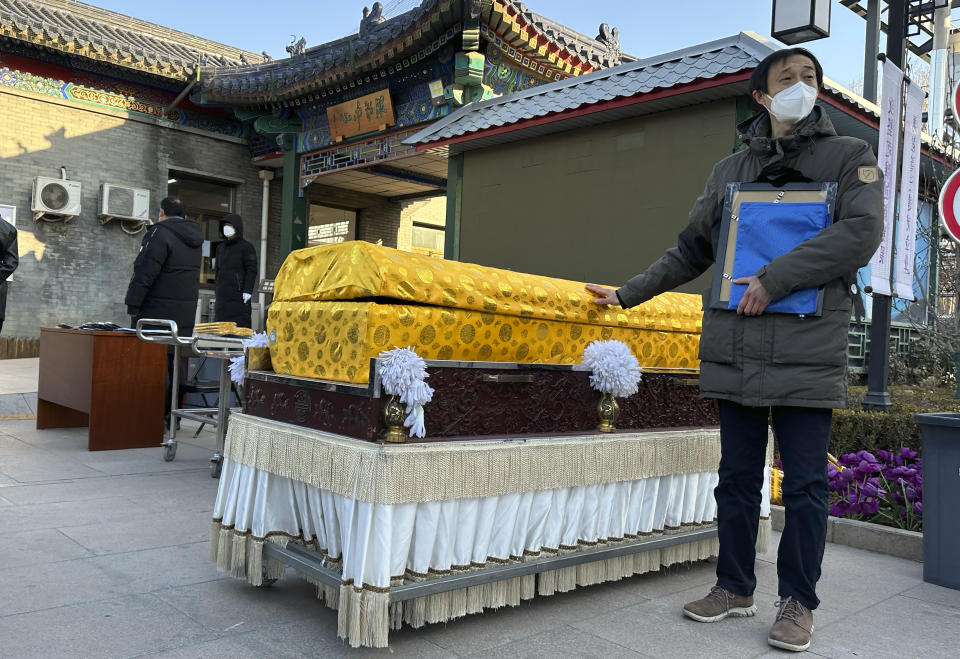 FILE - Family members in protective gear collect the cremated remains of their loved one bundled with yellow cloth at a crematorium in Beijing, Dec. 17, 2022. China's sudden reopening after two years holding to a "zero-COVID" strategy left older people vulnerable and hospitals and pharmacies unprepared during the season when the virus spreads most easily, leading to many avoidable deaths, The Associated Press has found. (AP Photo/Ng Han Guan, File)