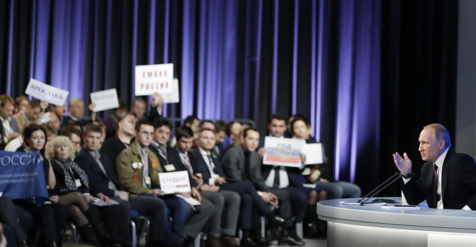 Russian President Vladimir Putin gestures as journalists show their posters with questions to him during his annual news conference in Moscow, Russia, Friday, Dec. 23, 2016. (AP Photo/Pavel Golovkin)