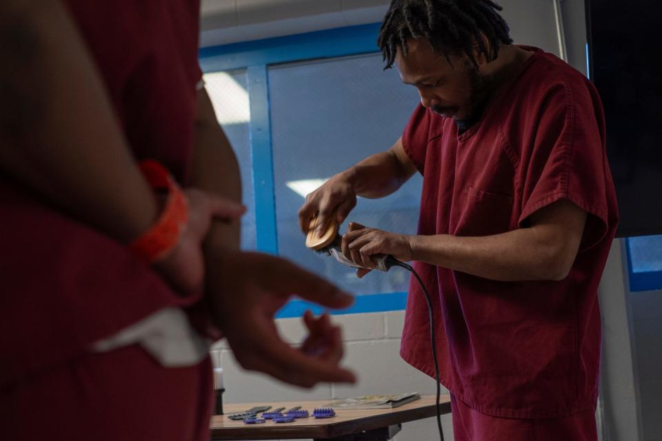 Shaqur Brewer, works to clean a pair of clippers as others look on during a one-hour barber course for a small group of incarcerated men as part of the I.G.N.I.T.E. (Inmate Growth Naturally and Intentionally Through Education) program held in an activities room of the Genesee County Jail in Flint on Thursday, Jan. 4, 2024.