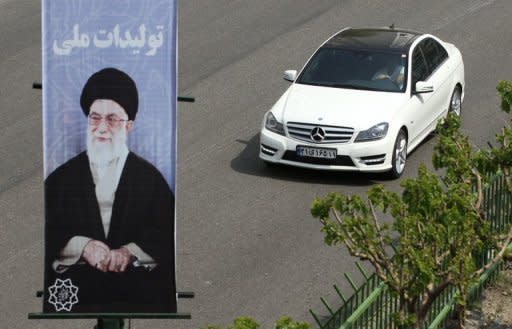 An Iranian man drives a Mercedes past a portrait of Iran's supreme leader, Ayatollah Ali Khamenei in northern Tehran on Sunday. Wealthy Iranians are fuelling an unprecedented luxury car boom despite sanctions hurting their economy, paying up to $360,000 for high-end autos, according to showroom employees and reports on Sunday