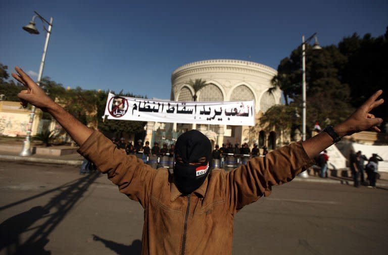 A masked supporter of the Egyptian opposition makes victory signs outside the gates of the presidential palace in Cairo. The main opposition bloc, the National Salvation Front, has said it is ready for "serious and objective dialogue" as soon as Mohamed Morsi met its demands to scrap both the decree and the referendum