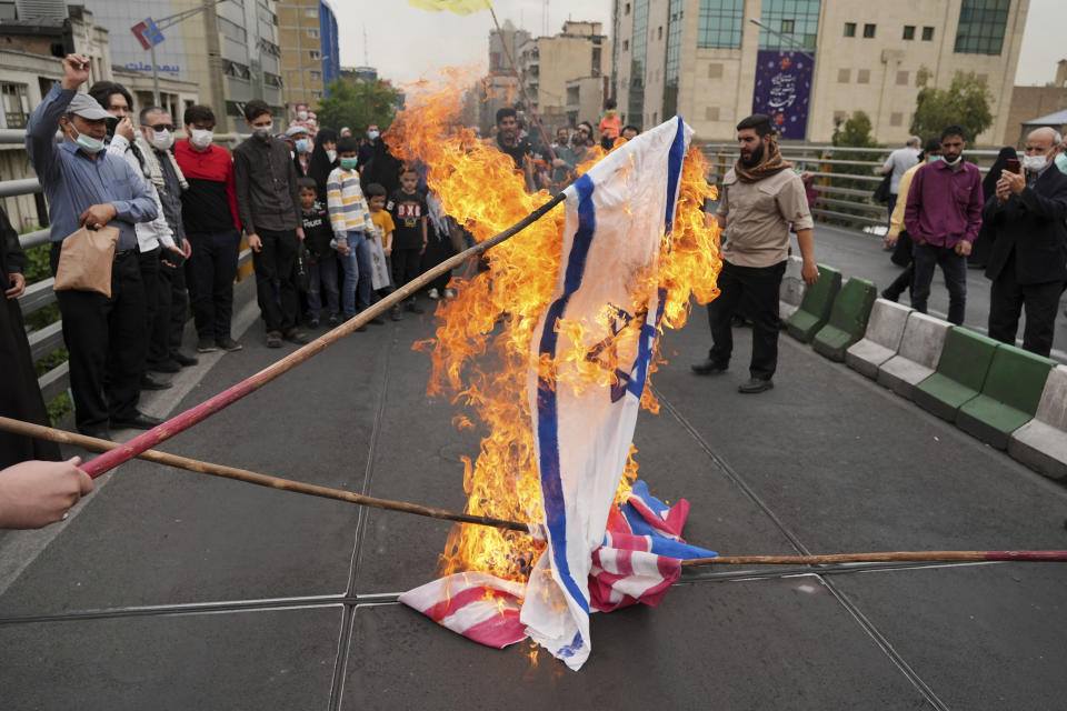 Demonstrators burn representations of Israeli, British and U.S. flags during the annual pro-Palestinians Al-Quds, or Jerusalem, Day rally in Tehran, Iran, Friday, April 29, 2022. Iran does not recognize Israel and supports Hamas and Hezbollah, militant groups that oppose it. (AP Photo/Vahid Salemi)