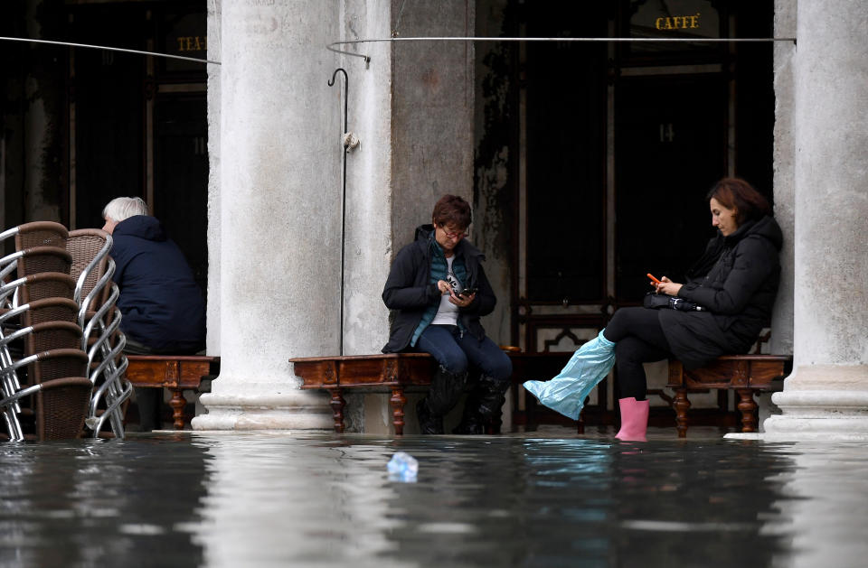 People sit outside a cafe under arcades at St. Mark's Square during high tide in Venice, Italy, on Nov. 17, 2019.&nbsp; (Photo: Alberto Lingria / Reuters)