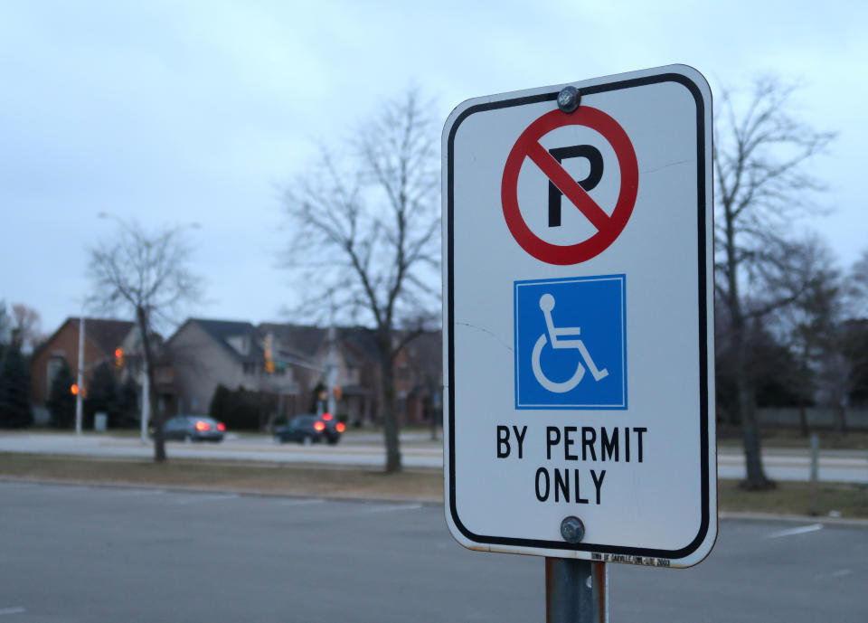 A sign outside that says "No parking by permit online" with a handicapped image