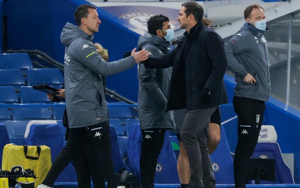 Terry greets then-Chelsea boss Frank Lampard on the sidelines at Stamford Bridge last year - NMC POOL