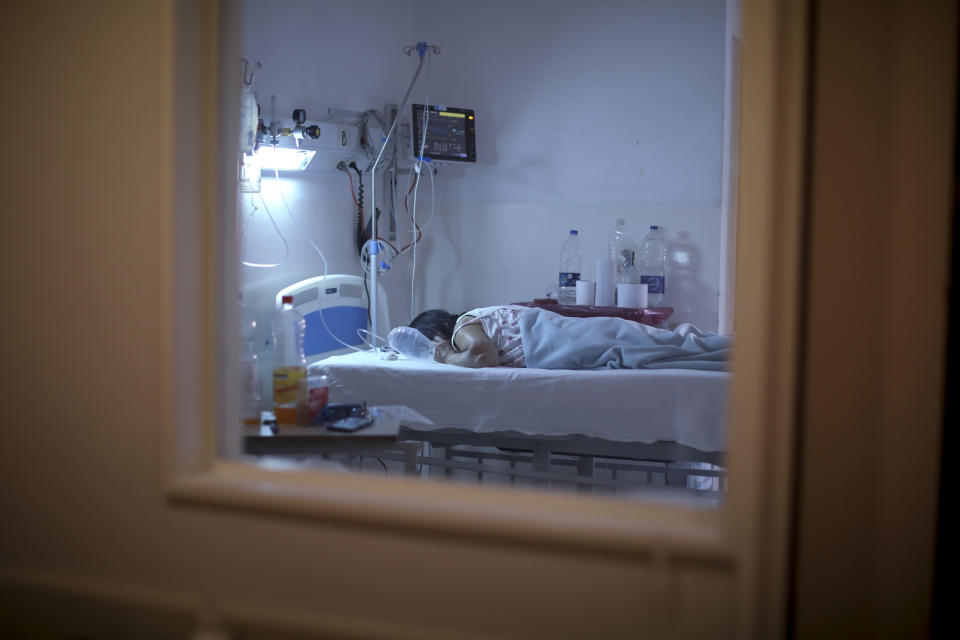 A patient with COVID-19 lies on a bed at the Eurnekian Ezeiza Hospital in Buenos Aires, Argentina, Thursday, Aug. 13, 2020. At a time when the number of deaths due to COVID-19 has increased in Argentina, some hospitals are now allowing persons, fully decked out in protective gear, to accompany their dying relatives. (AP Photo/Natacha Pisarenko)