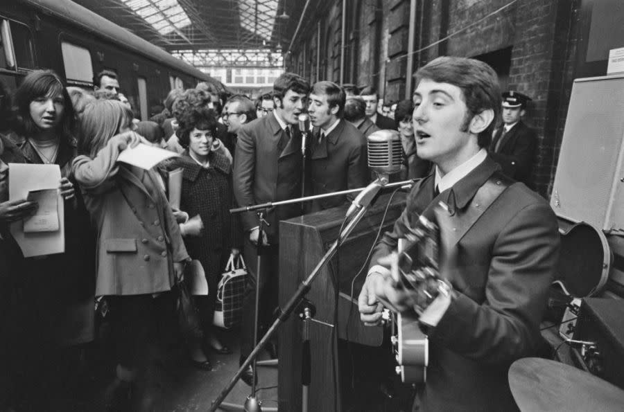 English rock band the Moody Blues perform live at Holborn Viaduct station in London, UK, 11th November 1964. Singer Denny Laine is in the foreground, with Ray Thomas (left) and Clint Warwick (right) in the background. (Photo by Evening Standard/Hulton Archive/Getty Images)