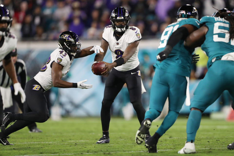 JACKSONVILLE, FLORIDA – DECEMBER 17: Lamar Jackson #8 of the Baltimore Ravens hands the ball to Justice Hill #43 during the second quarter against the Jacksonville Jaguars at EverBank Stadium on December 17, 2023 in Jacksonville, Florida. (Photo by Courtney Culbreath/Getty Images)