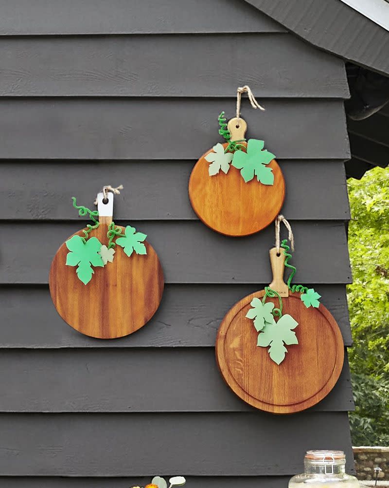 <p>Fashion pumpkins from round wood cutting boards stained with orange wood stain. Craft leaves from green kraft paper and tendrils from green pipe cleaners.</p>