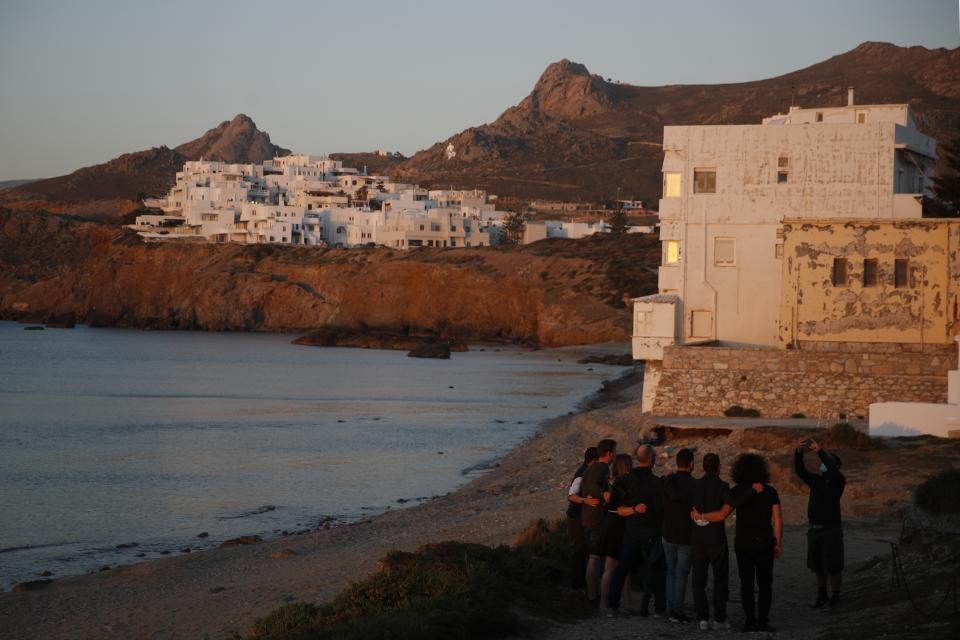 A company of tourists pose for a photograph as the sun sets in Chora, on the Aegean island of Naxos, Greece, Thursday, May 13, 2021. With debts piling up, southern European countries are racing to reopen their tourism services despite delays in rolling out a planned EU-wide travel pass. Greece Friday became the latest country to open up its vacation season as it dismantles lockdown restrictions and focuses its vaccination program on the islands. (AP Photo/Thanassis Stavrakis)