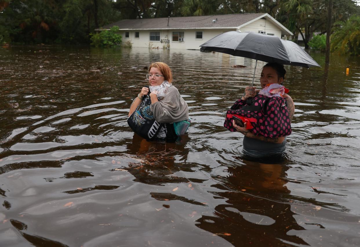 Makatla Ritchter (L) and her mother, Keiphra Line wade through flood waters after having to evacuate their home when the flood waters from Hurricane Idalia inundated it on 30 August 2023 in Tarpon Springs, Florida (Getty Images)