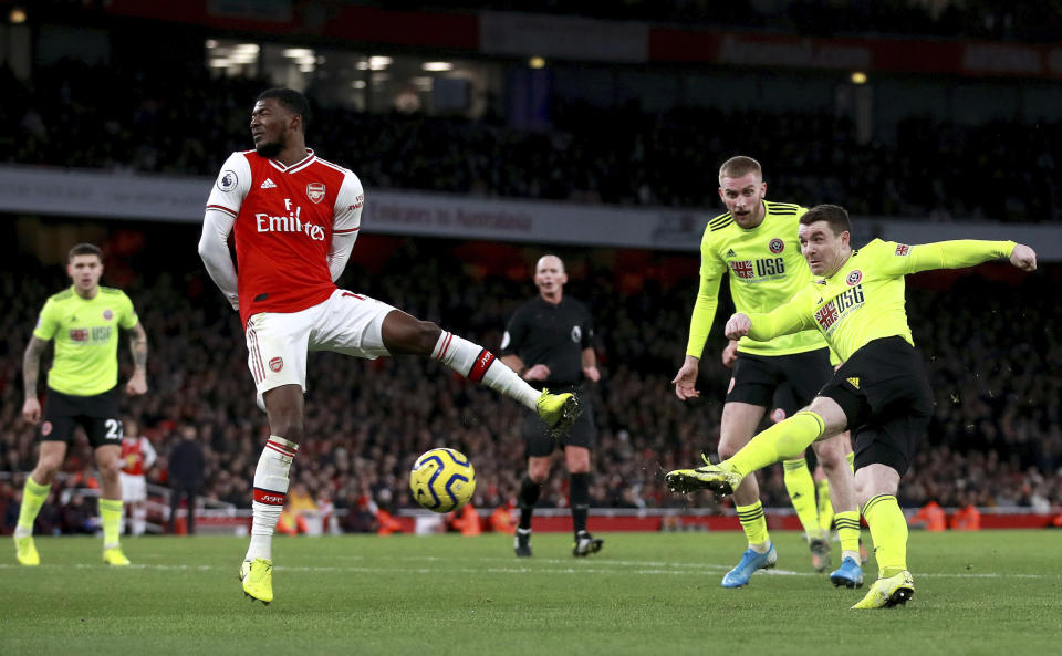 Sheffield United's John Fleck, right, scores his sides first goal past Arsenal's Ainsley Maitland-Niles during the English Premier League soccer match between Arsenal and Sheffield United at the Emirates Stadium, London, Saturday, Jan. 18, 2020. (Adam Davy/PA via AP)