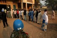 A United Nations security officer keeps guard as people wait in line to cast their votes during the second round of presidential and legislative elections in the mostly Muslim PK5 neighbourhood of Bangui, Central African Republic, February 14, 2016. REUTERS/Siegfried Modola