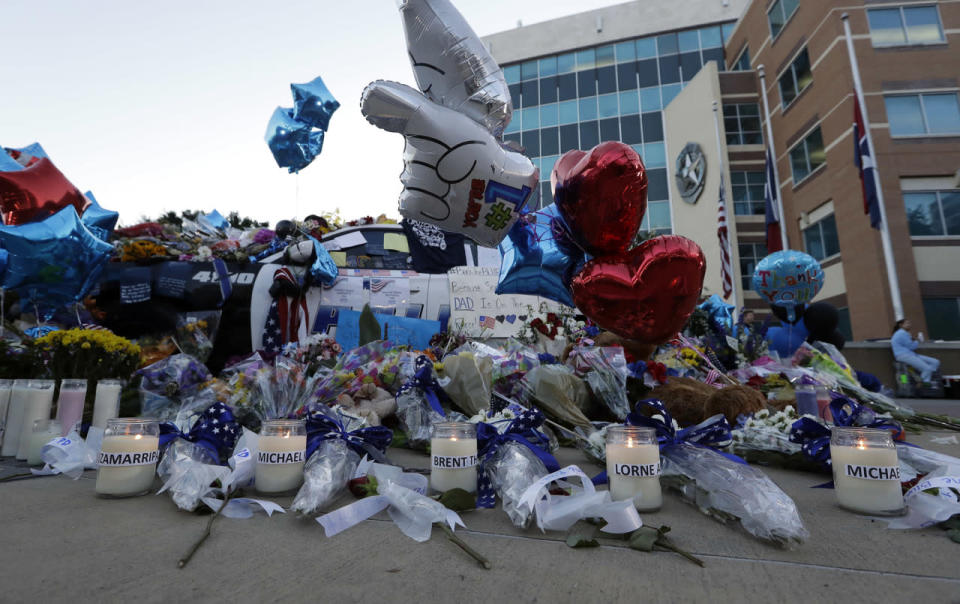 Two Dallas police patrol cars are covered with notes, flowers, balloons and other items as part of a makeshift memorial