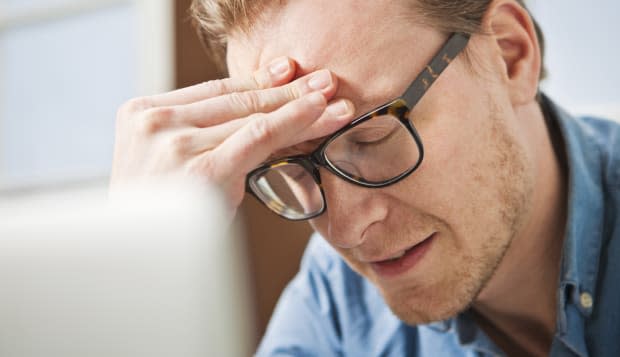 Man sitting at laptop, looking stressed