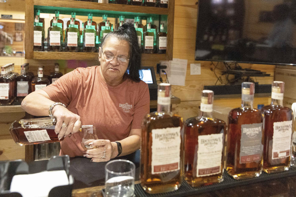 Bartender June Davis pours drinks inside the Hochatown Distilling Co. bar in Broken Bow, Okla. on Thursday, April 20, 2023. The growing optimism of McCurtain County's tourism boom over the last two decades took a gut punch last week when the local newspaper identified several county officials, including the sheriff and a county commissioner, who were caught on tape discussing killing journalists and lynching Black people. (AP Photo/Alonzo Adams)