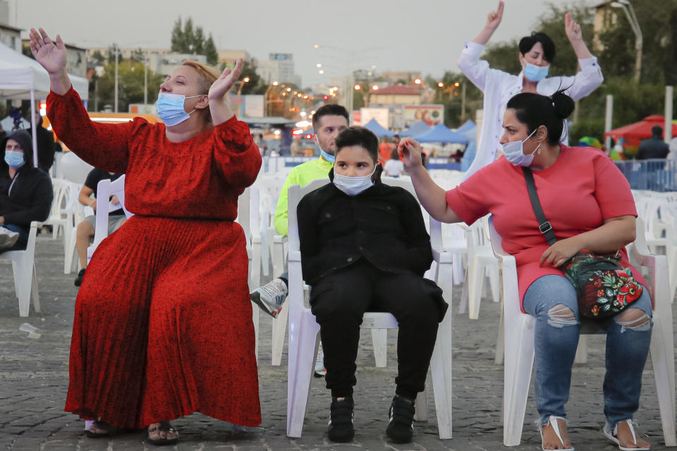 People wearing face masks for protection against the COVID-19 infection attend an outdoor concert, in Bucharest, Friday, Sept. 18, 2020.(AP Photo/Vadim Ghirda)