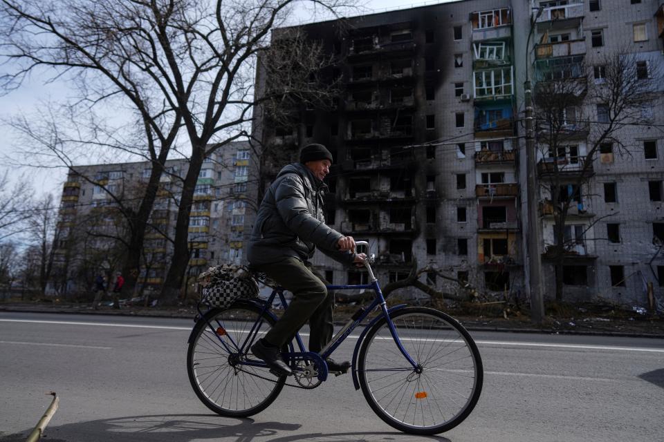 A man rides a bicycle past an apartment building damaged by shelling of Russian forces on the outskirts of Chernihiv, Ukraine, on April 7, 2022.