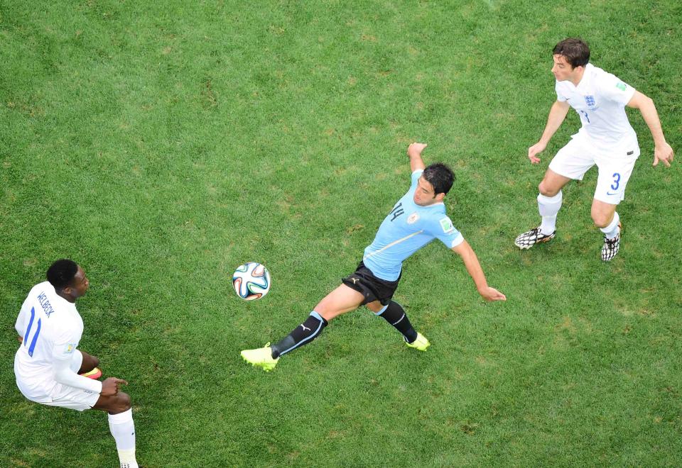 Uruguay's Lodeiro kicks the ball next to England's Welbeck (and England's Baines during their 2014 World Cup Group D soccer match at the Corinthians arena in Sao Paulo
