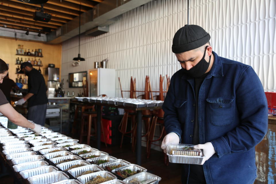 This image released by The Power of 10 shows chef Erik Bruner-Yang helping to pack meals at Cane, the first restaurant to reopen under The Power of 10, for hospital workers at Medstar Washington Hospital Center in Washington, D.C. Bruner-Yang established The Power of 10, an non-profit initiative that seeks donations to re-employ independent restaurant workers, keep the eateries open and provide their meals to neighborhood frontline workers. (Vina Sananikone/The Power of 10 via AP)