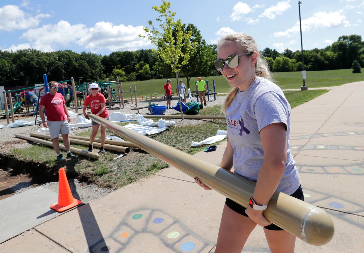 Volunteers Sarah Reynolds, left, a physical therapist with the Hortonville School District, and Tessa Keller, a teacher at North Greenville Elementary School, carry a post that will be an anchor point for a swing set on the new playground at Hortonville Elementary School.