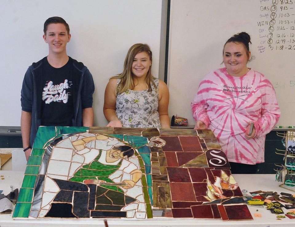 (Left to right) Josh Smucker, Taylor Rohrer and Savannah Messenger hold a stained glass window project the Smithie Art Club worked on last school year. The window now hangs in the classroom of art teacher Jennifer Winkler who recently got roughly $13,7000 in grant money approved which will go back into her classroom.