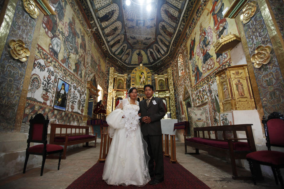 A couple poses for pictures after their wedding inside the Sistine Chapel of Los Andes in Curahuara de Carangas, Oruro department, 260 km. (160 miles) south from La Paz, Bolivia, Saturday, Dec. 8, 2012. The colonial-era house of worship known in Bolivia as the Sistine Chapel of the Andes, built in 1608 to evangelize indigenous Bolivians into the Roman Catholic faith, was filled with flowers over the weekend for those celebrating two weddings and seven baptisms on the wind swept mountain plateau. (AP Photo/Juan Karita)