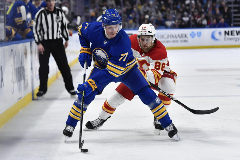 Buffalo Sabres left wing Victor Olofsson, left, skates with the puck in front of Calgary Flames left wing Andrew Mangiapane during the second period of an NHL hockey game in Buffalo, N.Y., Saturday, Feb. 11, 2023. (AP Photo/Adrian Kraus)