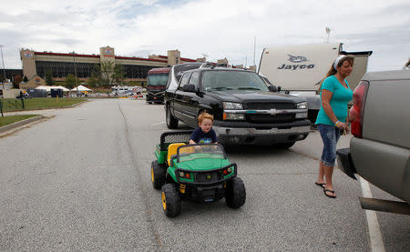 Four year old Brayden Screen rides his toy tractor as his grandmother Stephanie Giordano stands at their trailer after originally driving from Savannah, Georgia to ride out Hurricane Irma at Atlanta Motor Speedway in Hampton, Georgia, U.S., September 10, 2017. REUTERS/Tami Chappell