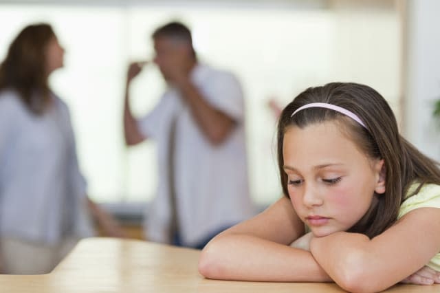 Sad looking girl with her fighting parents behind her