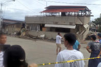 Residents look at a collapsed building following an earthquake that struck Padada, Davao del Sur province, southern Philippines on Sunday Dec. 15, 2019. A strong quake jolted the southern Philippines on Sunday, causing a three-story building to collapse and prompting people to rush out of shopping malls, houses and other buildings in panic, officials said. (AP Photo/John Angelo Jomao-as)