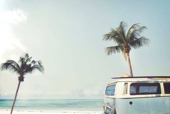 A minibus on the beach in front of two palm trees