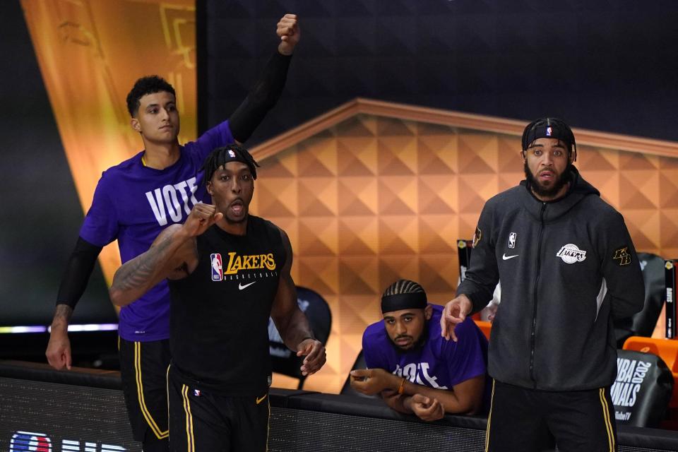 Los Angeles Lakers' Dwight Howard, left front, Kyle Kuzma, left rear, and JaVale McGee, right, celebrate in the closing seconds of Game 2 of basketball's NBA Finals against the Miami Heat on Friday, Oct. 2, 2020, in Lake Buena Vista, Fla. The Lakers won 124-114. (AP Photo/Mark J. Terrill)