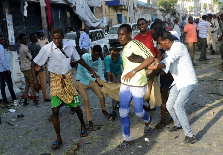 Somali people carry a man away from the scene of a car bombing attack in Mogadishu, Somalia, on March 22, 2018