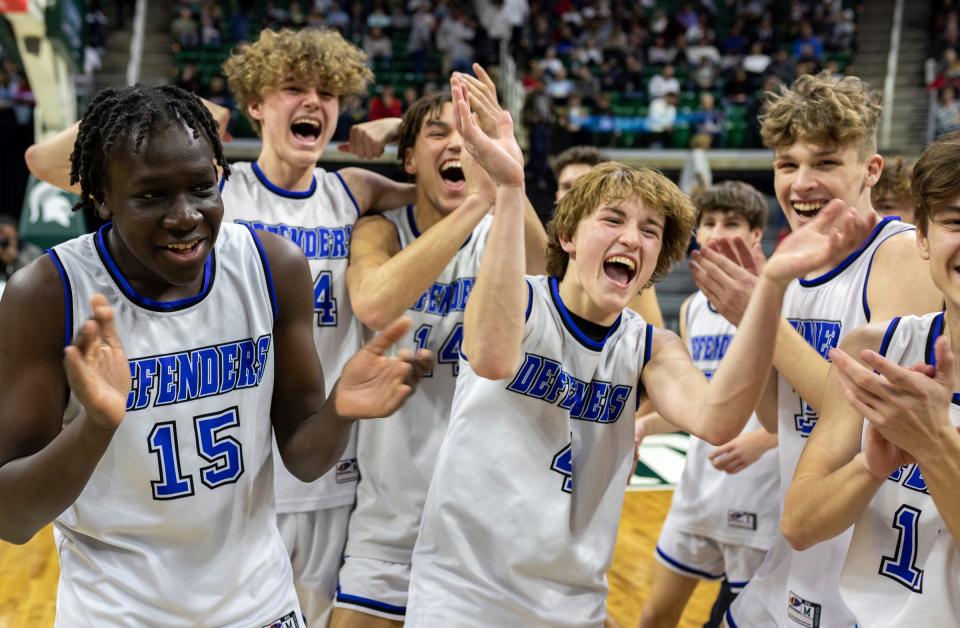 Wyoming Tri-unity Christian's Marcus Lokiden (15) and Keaton Blanker (4) celebrate with their teammates after defeating Mt. Pleasant Sacred Heart 79-59 during the MHSAA Div. 4 state finals at the Breslin Center in East Lansing on March 16, 2024.