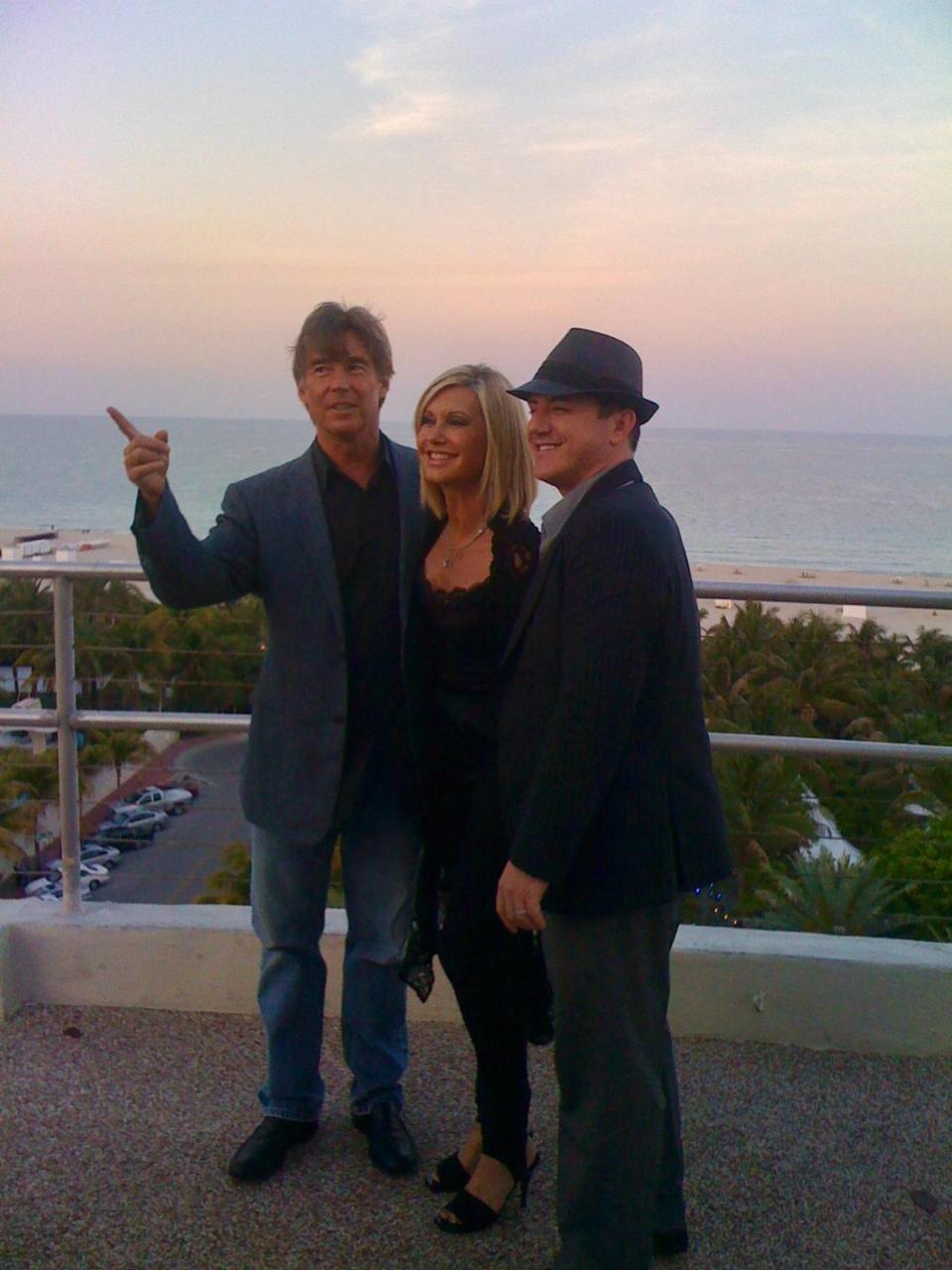 Olivia Newton-John was flanked by two of the most important men in her life at the time of this photo from April 22, 2010. Here, the singer is flanked by her husband John Easterling (left) and her longtime publicist and close friend Michael Caprio, atop The Raleigh Hotel on Miami Beach. Newton-John was there to perform a cancer charity benefit alongside Barry Gibb and Jon Secada later that evening.