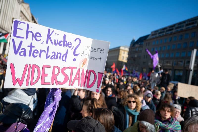 Participants stand on the street Unter den Linden during a demonstration for International Women's Day, holding a placard reading " Our answer resistance!". Several more demonstrations and rallies are planned in the capital until the evening. Christophe Gateau/dpa