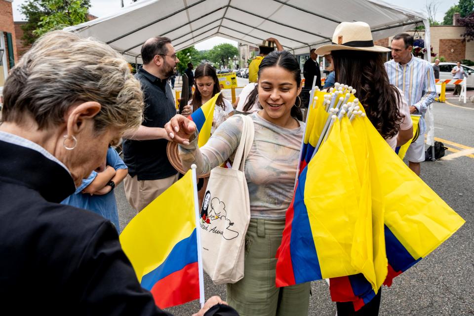 Nayva Chia hands out Columbian flags at the Ridgewood Pedestrian Plaza on Saturday, June 3, 2023. The plaza will be closed to automobiles on Saturdays and Sundays through October of 2023. 