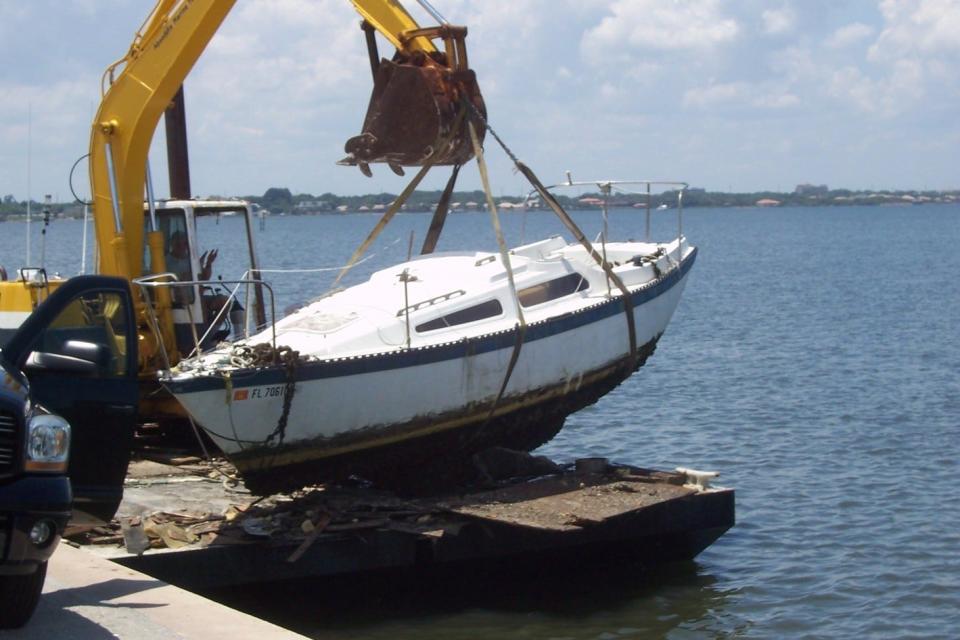 A boat is removed from the water as part of Brevard County's program to reduce the number of abandoned boats in local waterways.