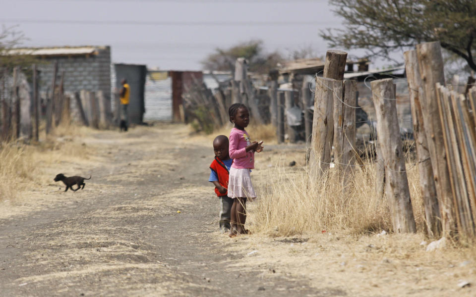 FILE In this photo taken Tuesday, Aug. 28, 2012 children walk among miners shacks in the Wonderkop settlement next to the Lonmin Platinum Mine near Rustenburg, South Africa. The current unrest in the mining industry started in August with the miners staging a wildcat strike that led to a violent confrontation in which police shot and killed 34. More than 70 others were wounded in the worst case of of state-led violence since the end of apartheid. (AP Photo-File)