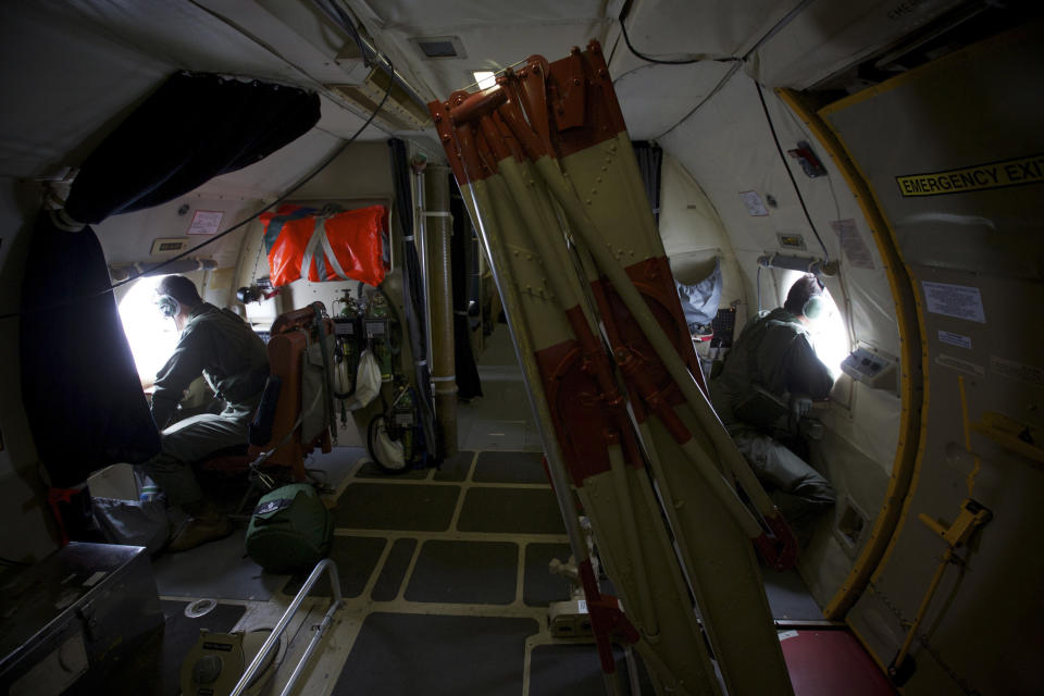 FILE - In this Monday, March 24, 2014 file photo, crewmen of an Royal Australian Air Force AP-3C Orion aircraft look out of their observation windows whilst searching for missing Malaysia Airlines Flight MH370 over the Indian Ocean. There are two spotters on either side of the aircraft. They rest their elbows on a padded shelf, their binoculars sitting at arm's reach. A small pocket near each window contains safety manuals, paperwork and a handful of barf bags. On at least one particularly bumpy flight, the crew had to use them. (AP Photo/Richard Wainwright, Pool, File)