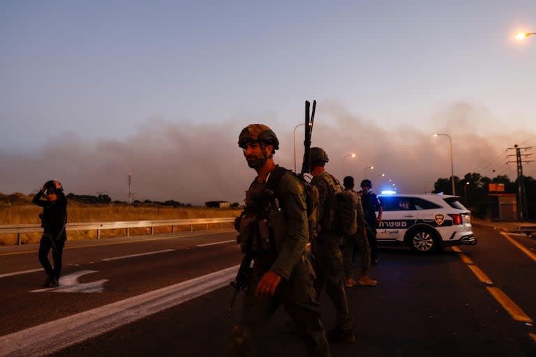 Soldados y policías israelíes aseguran una carretera mientras se lanzan cohetes desde el sur del Líbano en los Altos del Golán anexionados por Israel el 9 de julio de 2024, en medio de los continuos enfrentamientos transfronterizos entre las tropas israelíes y los combatientes de Hezbollah.