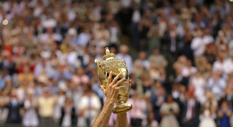 El suizo Roger Federer celebra con el trofeo después de vencer al croata Marin Cilic en el partido final individual masculino el día trece en el Campeonato de Tenis de Wimbledon en Londres el domingo 16 de julio de 2017. 