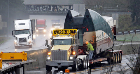 A damaged train car sits on a flatbed trailer after being removed from the scene of Monday's deadly Amtrak train crash onto Interstate 5 - Credit:  Elaine Thompson/ AP