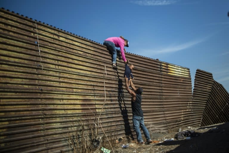 Central American migrants climb the border fence between Mexico and the United States in Tijuana, Mexico